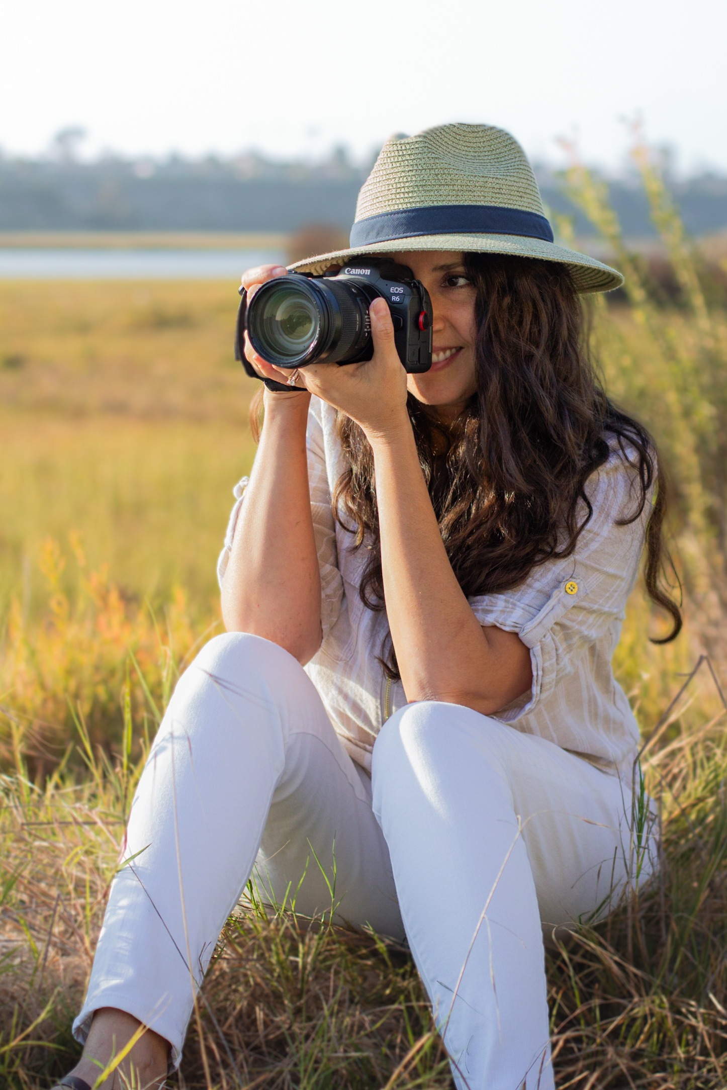 Maribel holding her Canon camera in a sunlit field