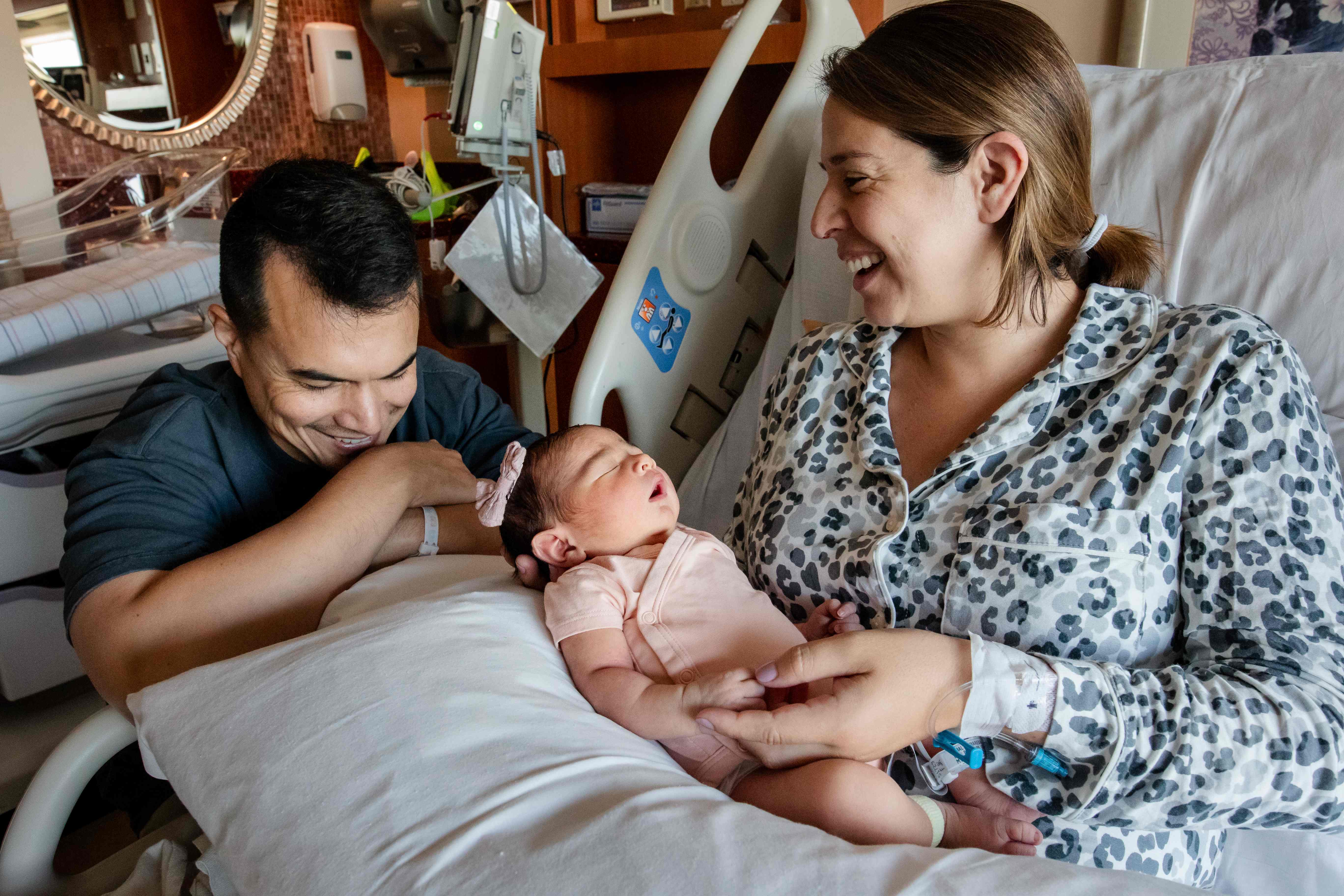 Two parents smiling down at their newborn in the hospital