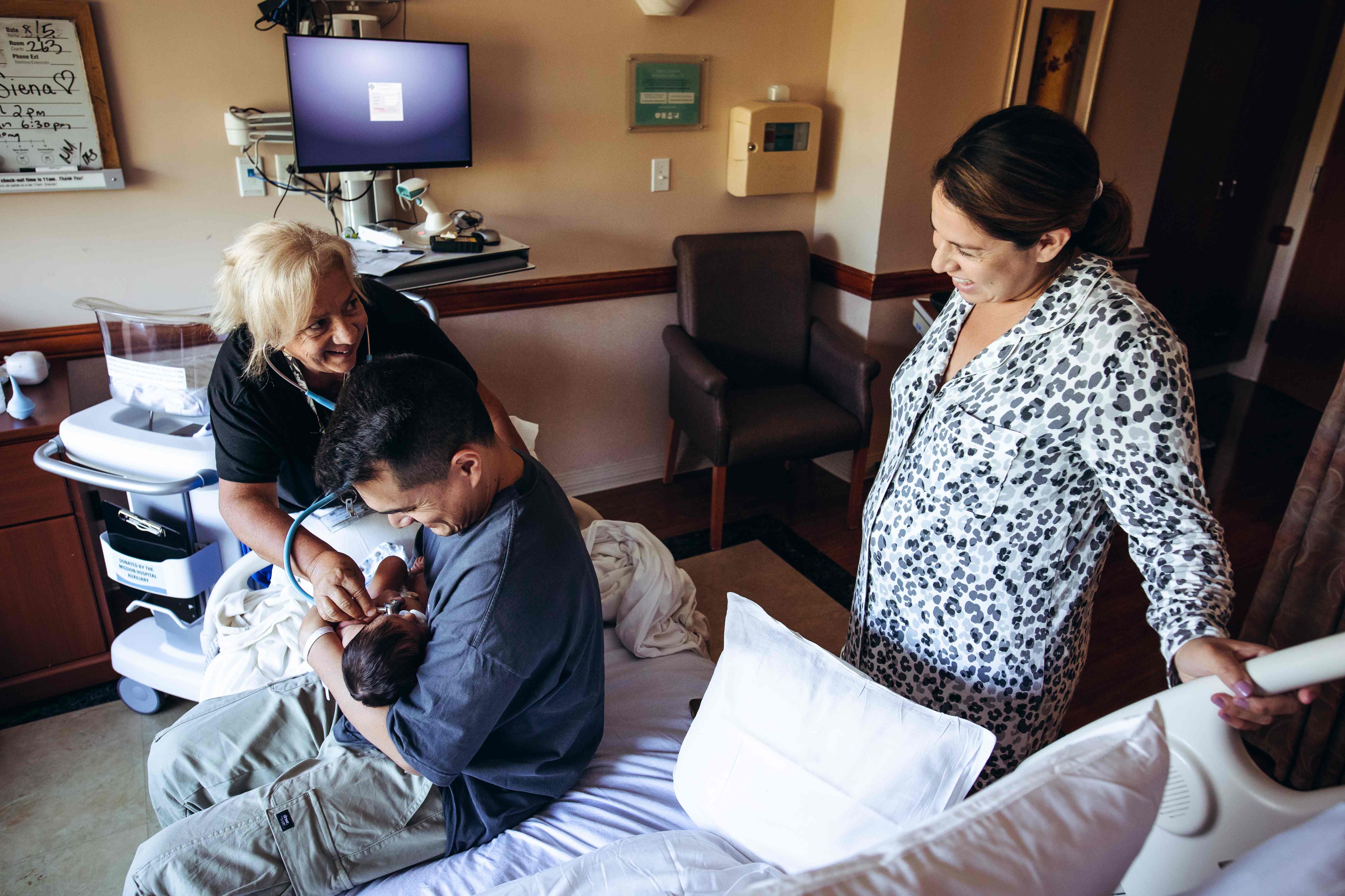 A nurse checking the newborn while the family looks on