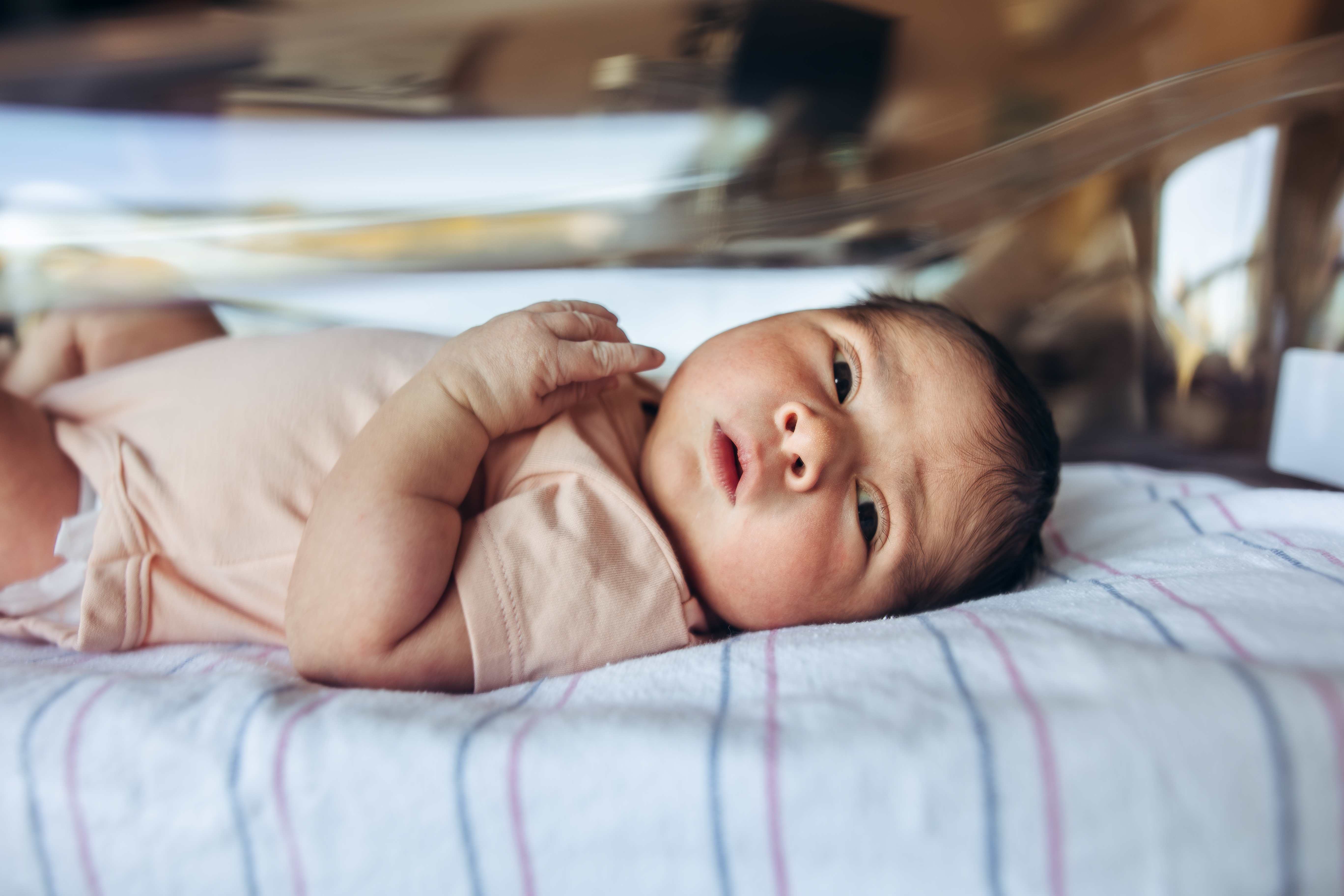 Close-up of an alert newborn resting in the bassinet