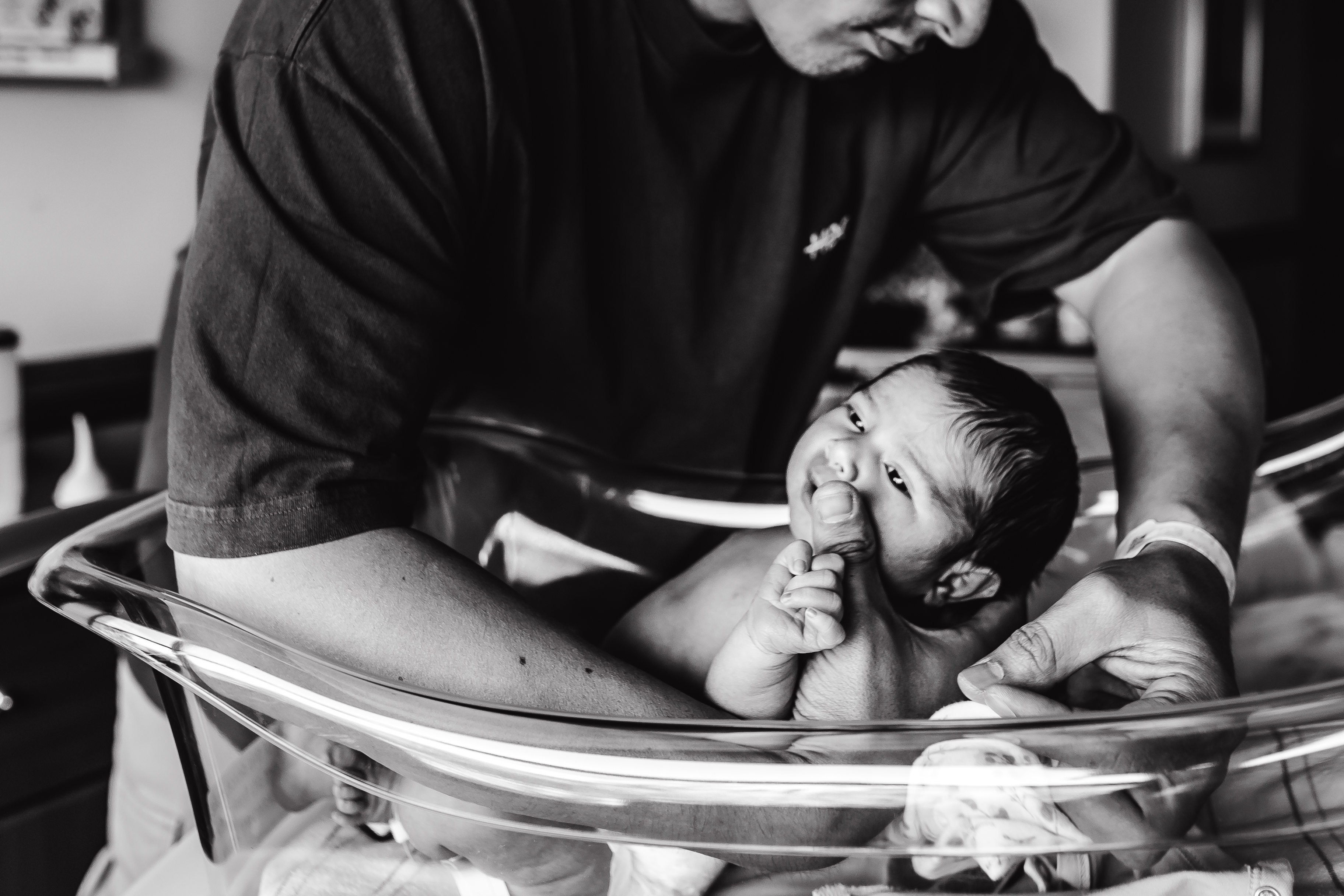 Black and white photo of a father with his newborn in the bassinet