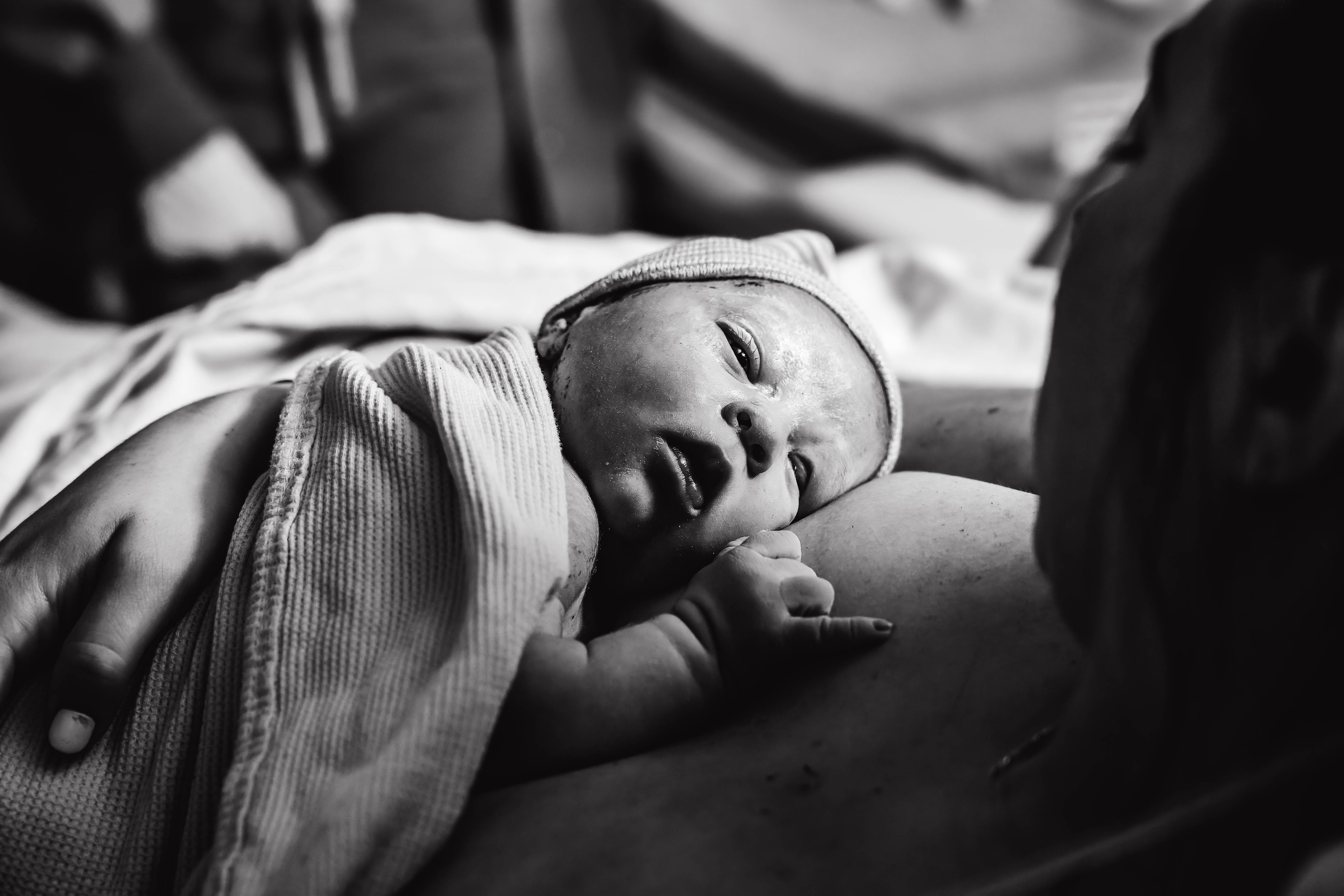 Black and white close-up of a newborn resting on mother's chest