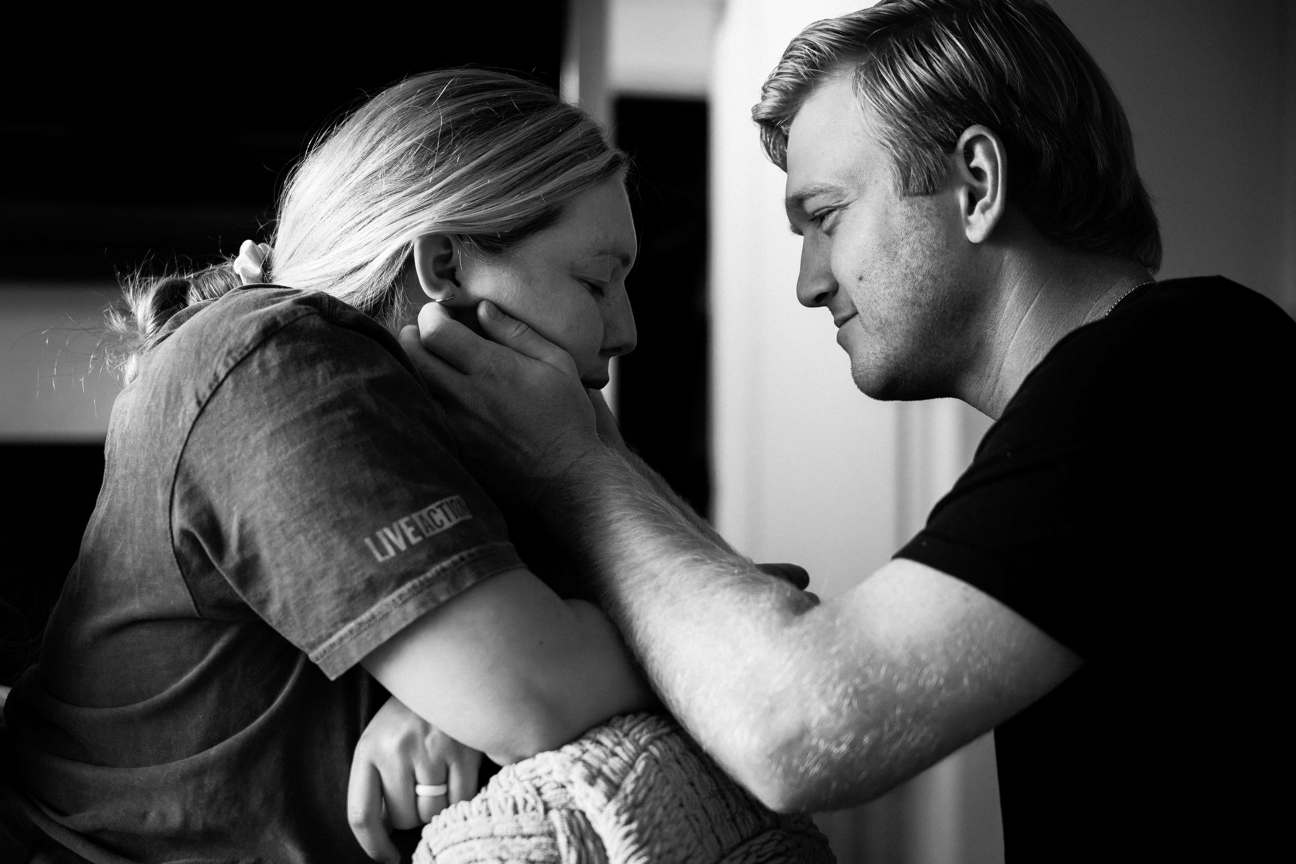Black and white photo of a partner cradling a laboring mother's face