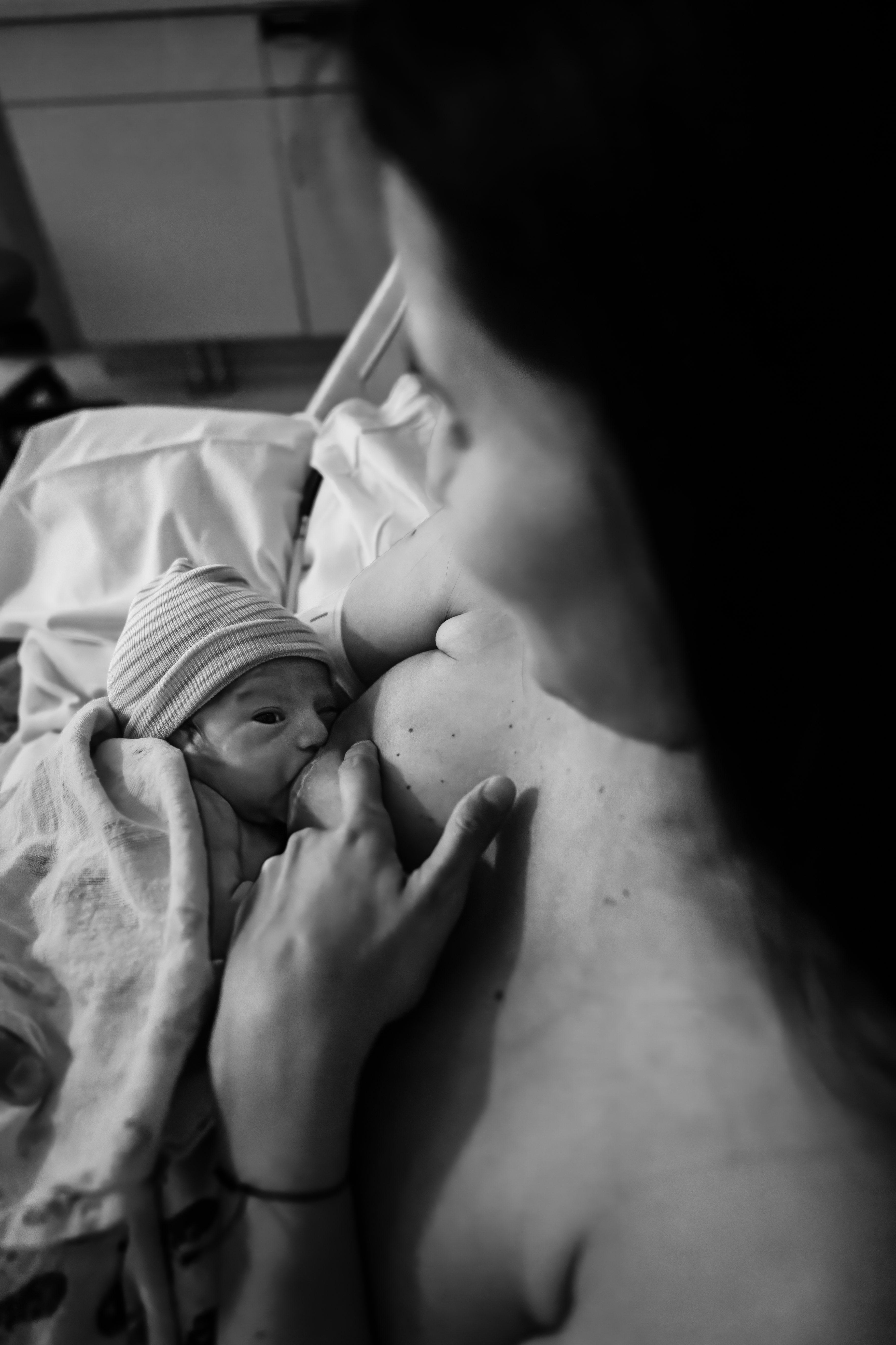 Black and white photo of a mother breastfeeding her newborn skin-to-skin