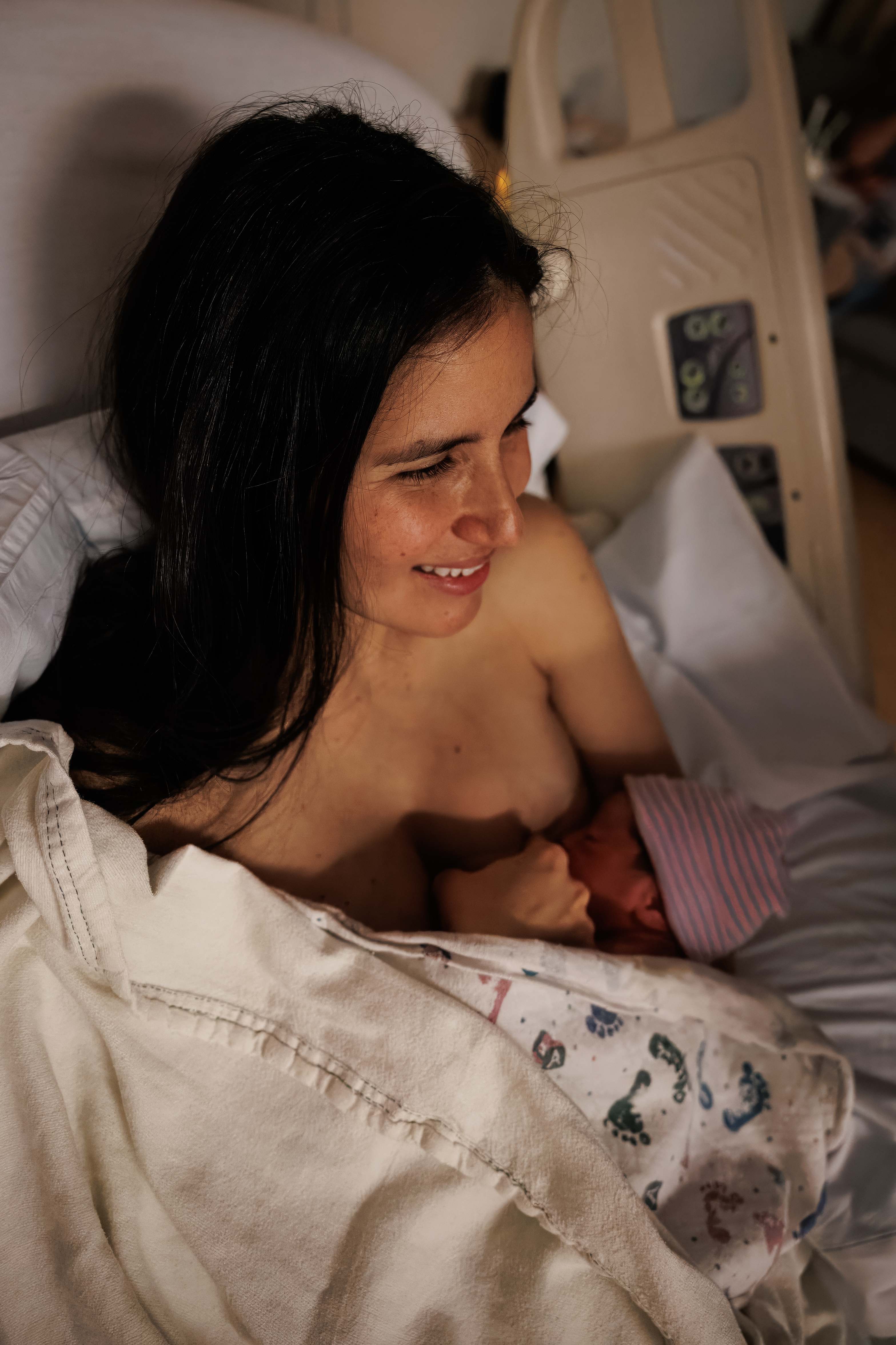 A mother gazing down at her breastfeeding newborn