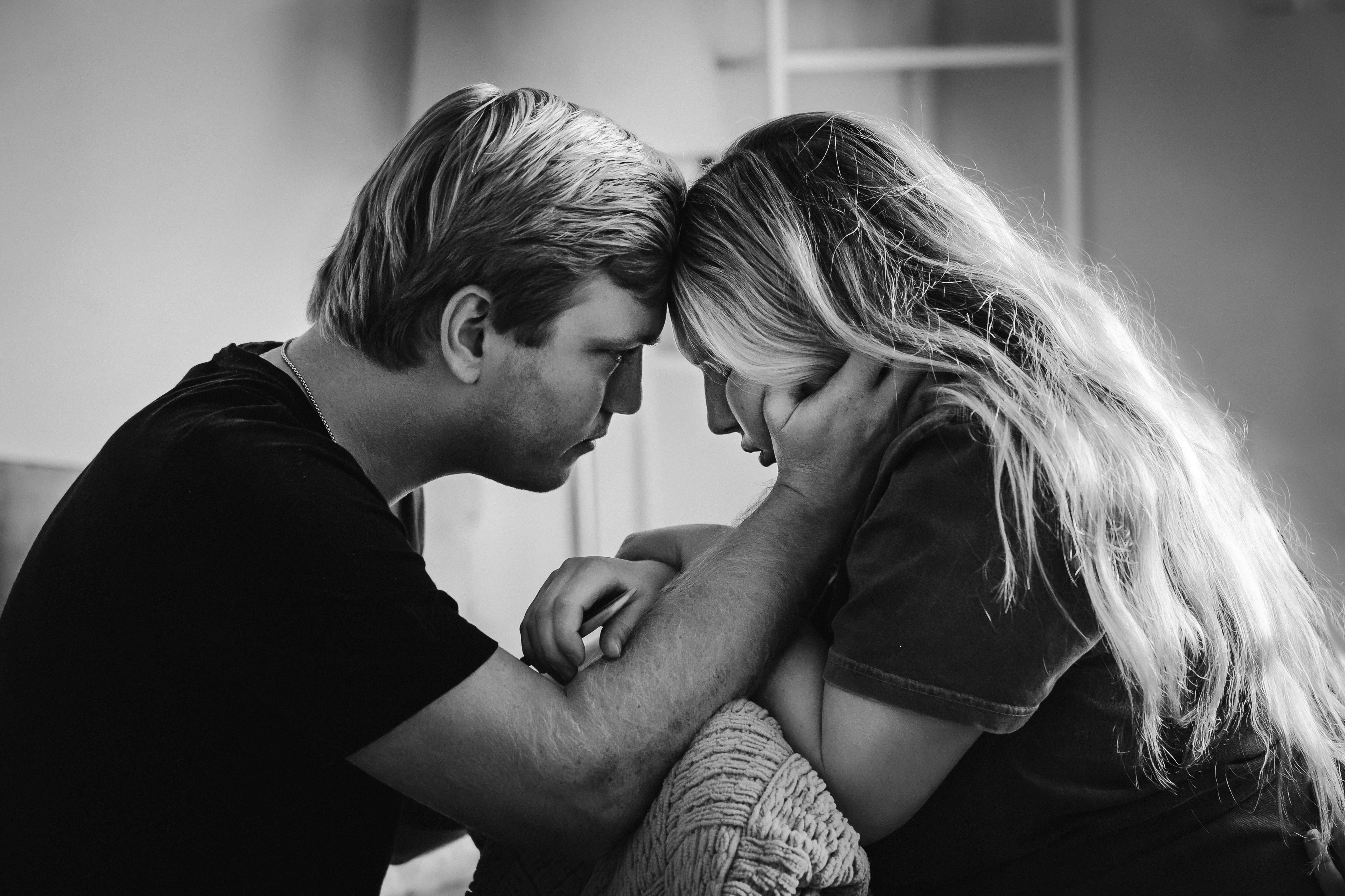 Black and white photo of a couple resting forehead to forehead during labor