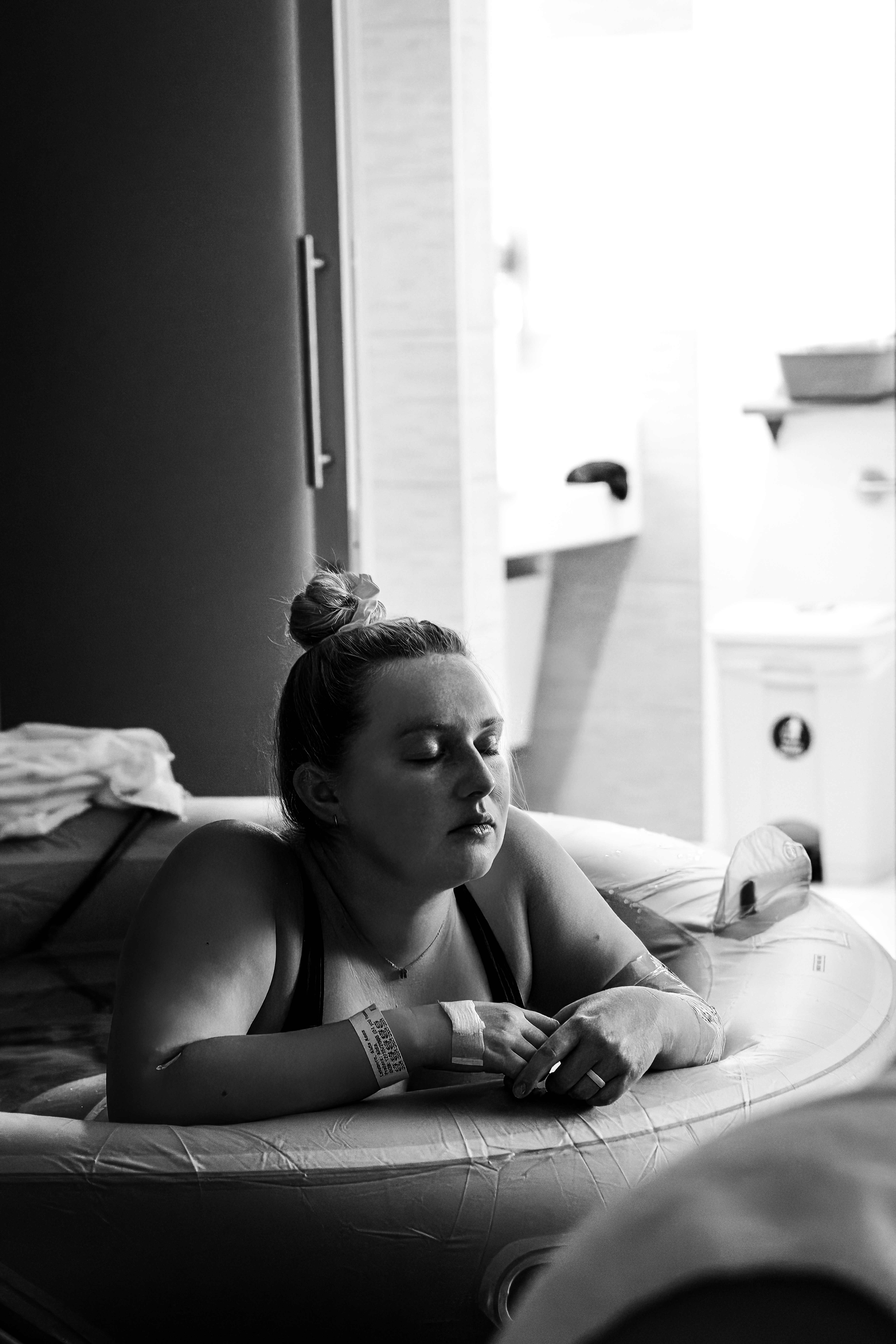 Black and white photo of a mother resting as she labors in the birth tub